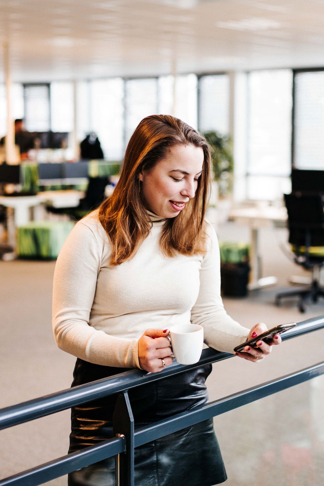 Een vrouw op kantoor kijkt op haar telefoon