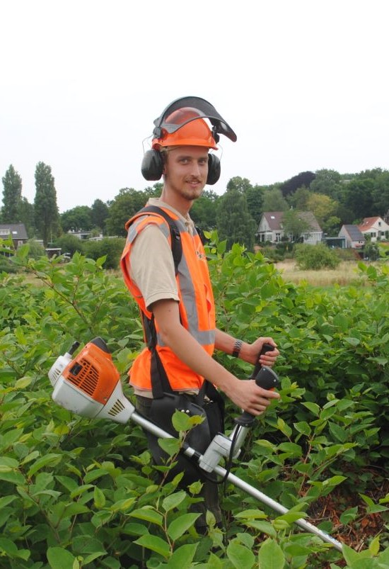 Een groenvoorziener die bezig is een weiland met het klein maken van het gras.